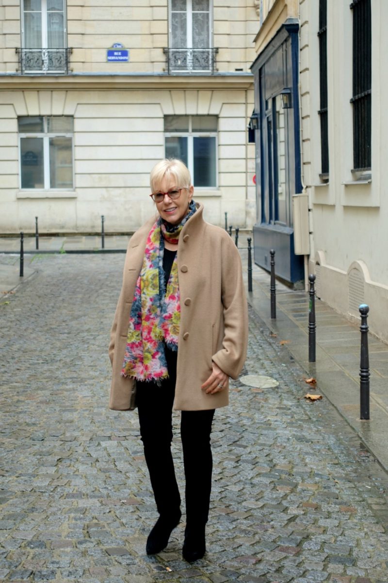 Susan B. wears a beige jacket from agnes b. in Paris.