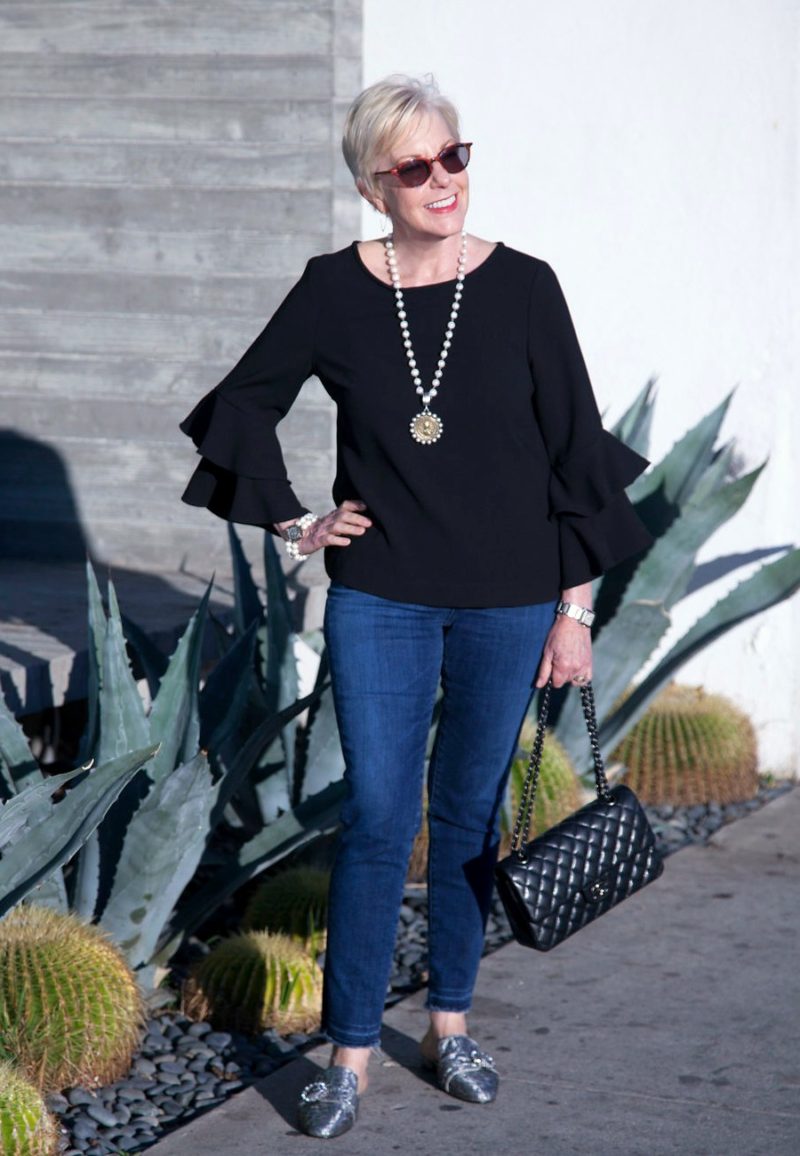 Susan B. wears a black tiered bell sleeve blouse, French Kande pearl necklace and Chanel flap bag. Details at une femme d'un certain age.