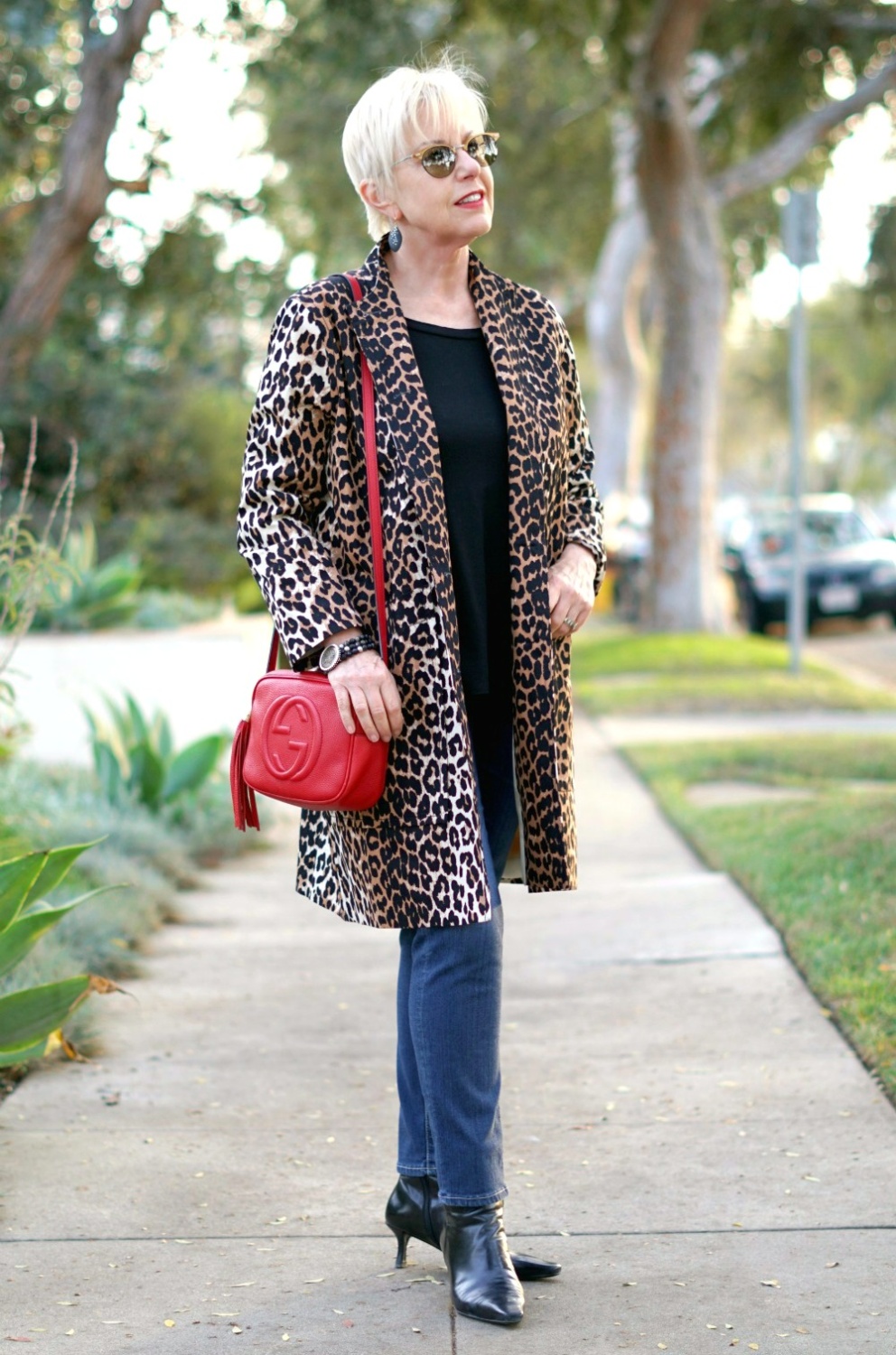 Susan B. wears a denim look with a lightweight leopard coat and red Gucci bag. Details at une femme d'un certain age.