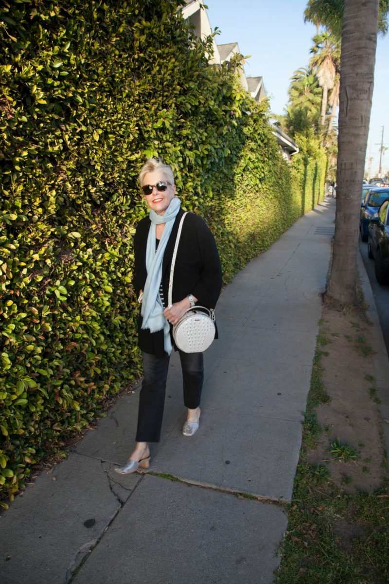 Wearing a pastel blue scarf, black jacket and metallic mules for a stroll in Venice Beach. Details at une femme d'un certain age.