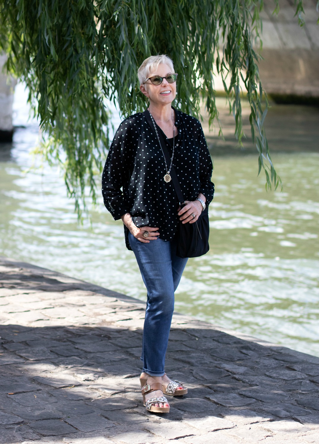 A Paris travel outfit: style and travel blogger Susan B. wears a black cotton top, jeans and wedge sandals. Details at une femme d'un certain age.