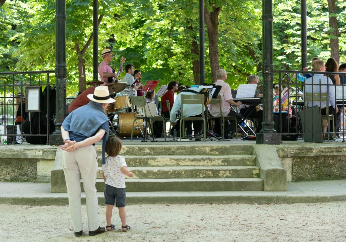 Man and boy listening to concert in Jardin du Luxembourg in Paris. Details at une femme d'un certain age.