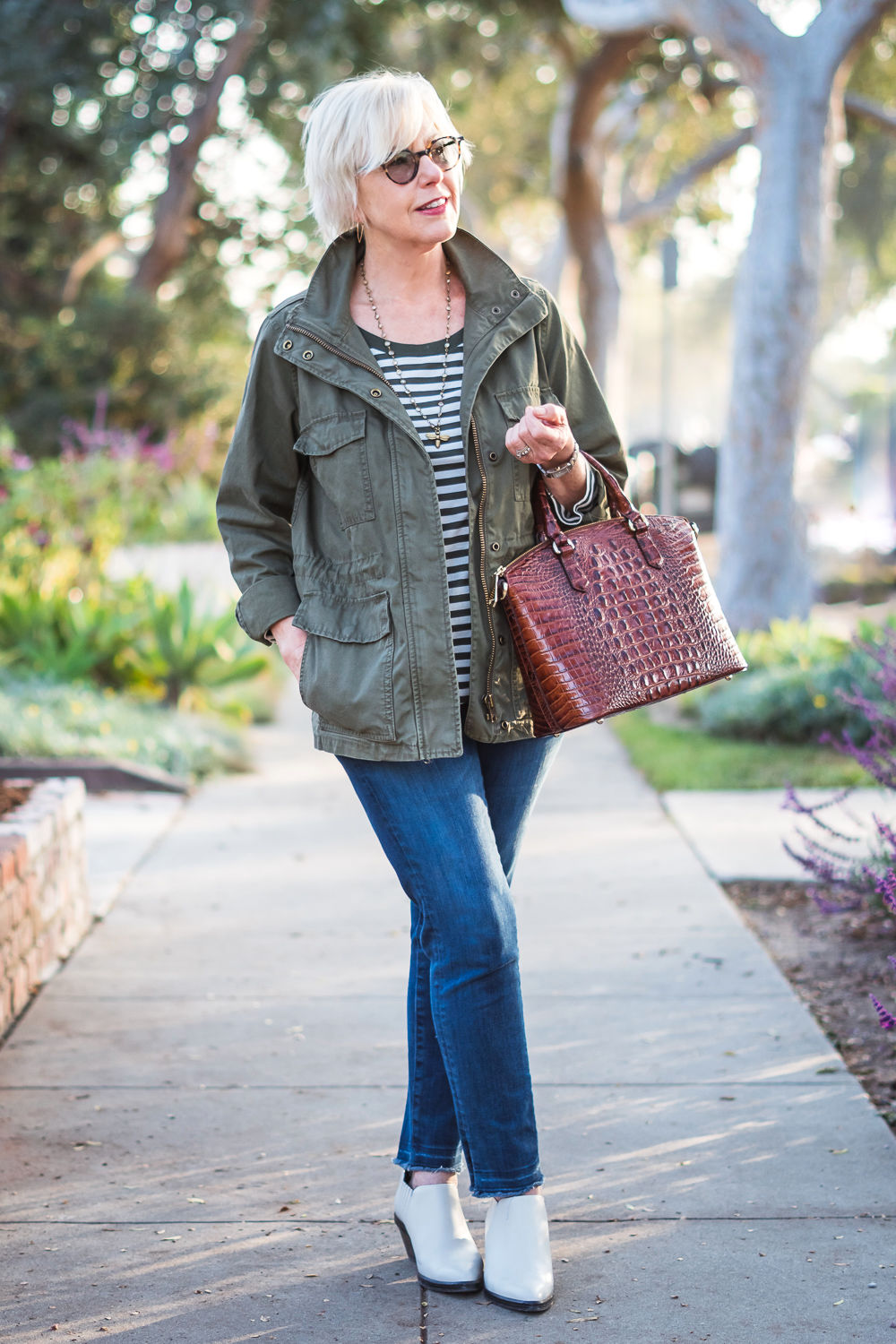 How to wear white boots with jeans: style blogger Susan B. wears a casual look with striped tee, utility jacket, jeans and white boots. Details at une femme d'un certain age.