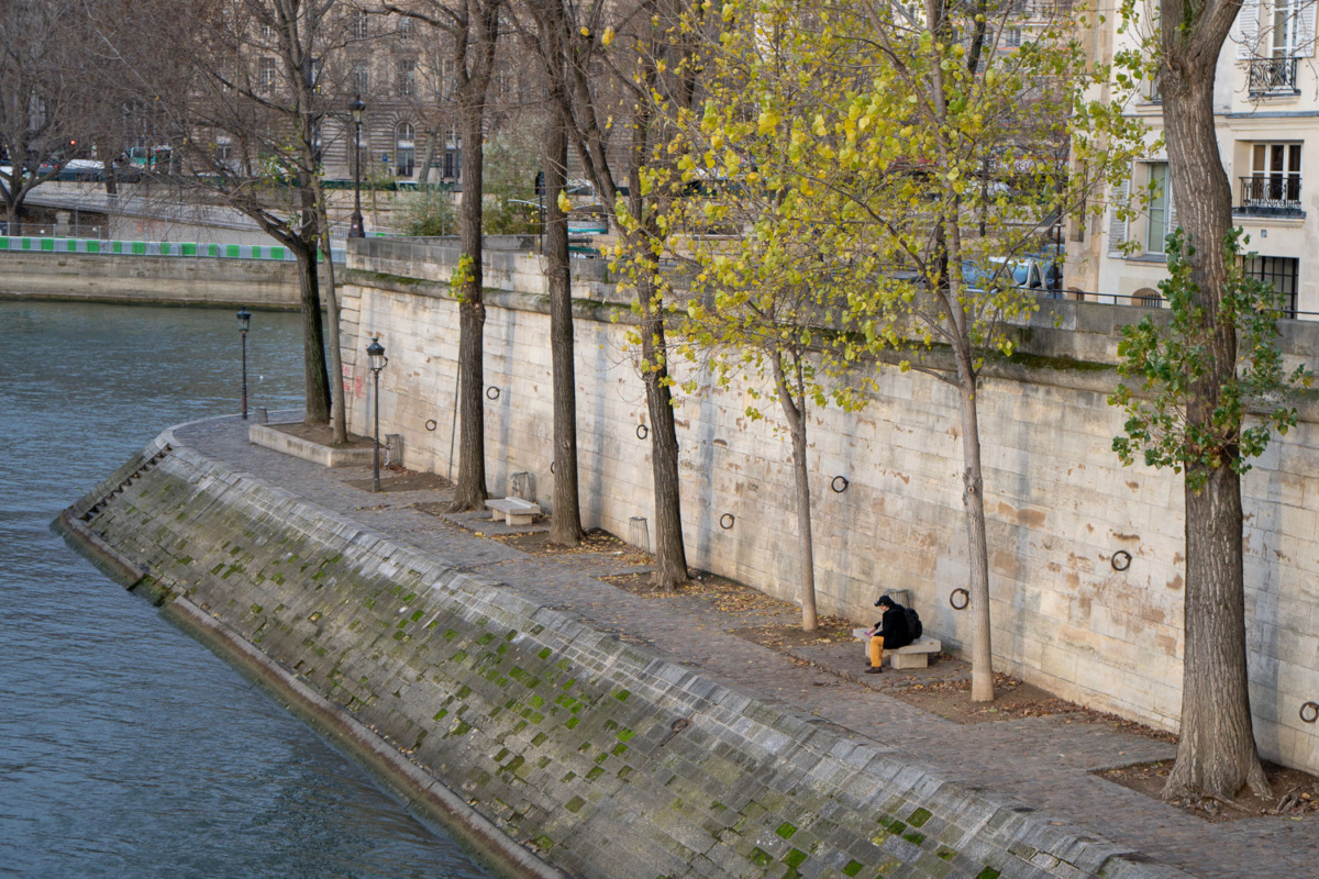 Person in yellow pants reading a book on the banks of the Seine, Ile St. Louis, Paris. Details at une femme d'un certain age.