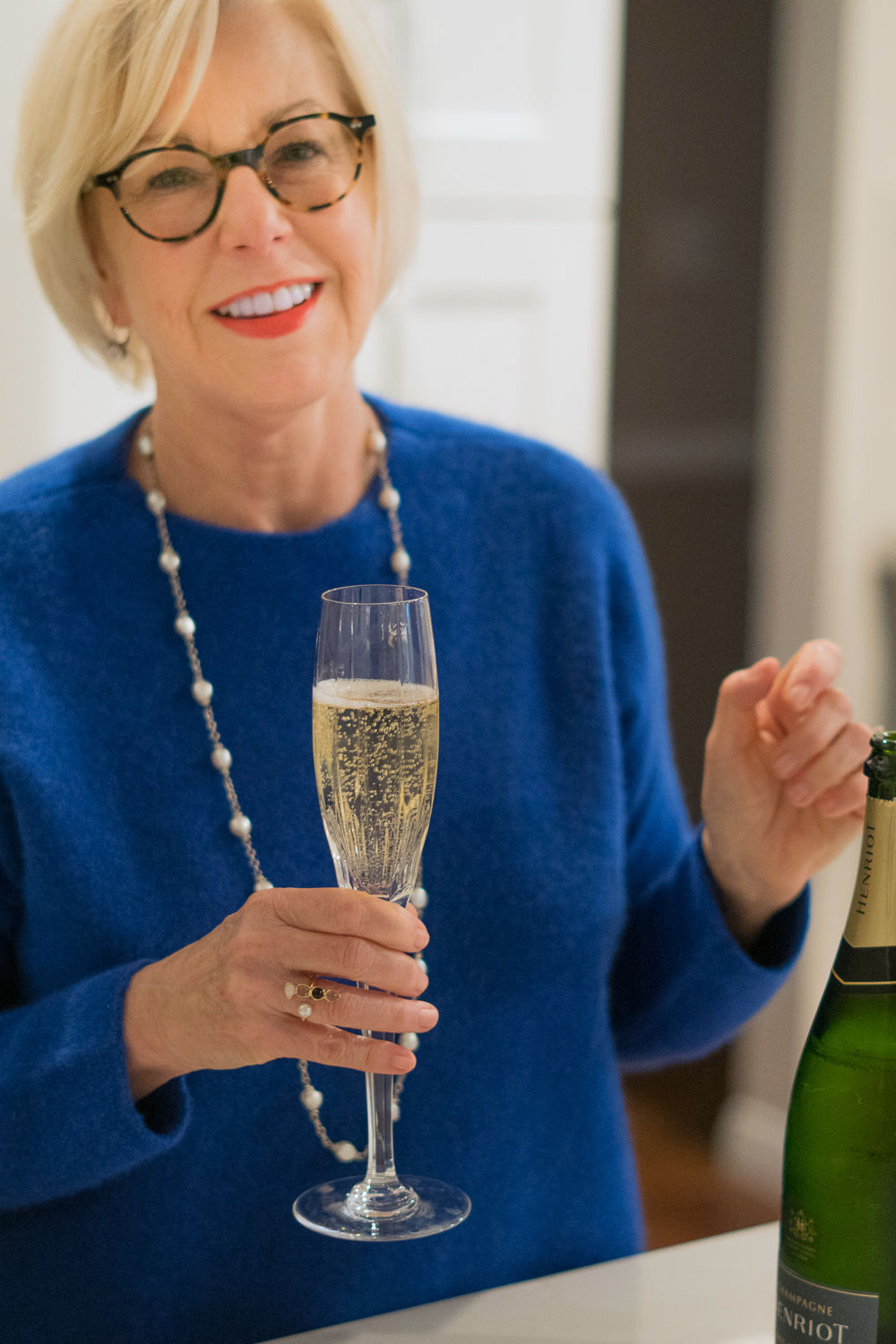 Style blogger Susan B. wearing a blue EILEEN FISHER sweater, silver and pearl necklace, and toasting the holidays with a glass of champagne. More at une femme d'un certain age.