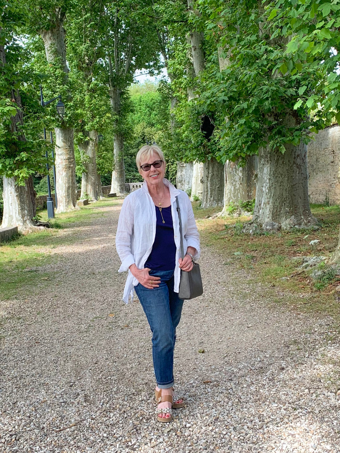 Susan B of une femme d'un certain age wears jeans, a white shirt and sandals for sightseeing in Beaune.