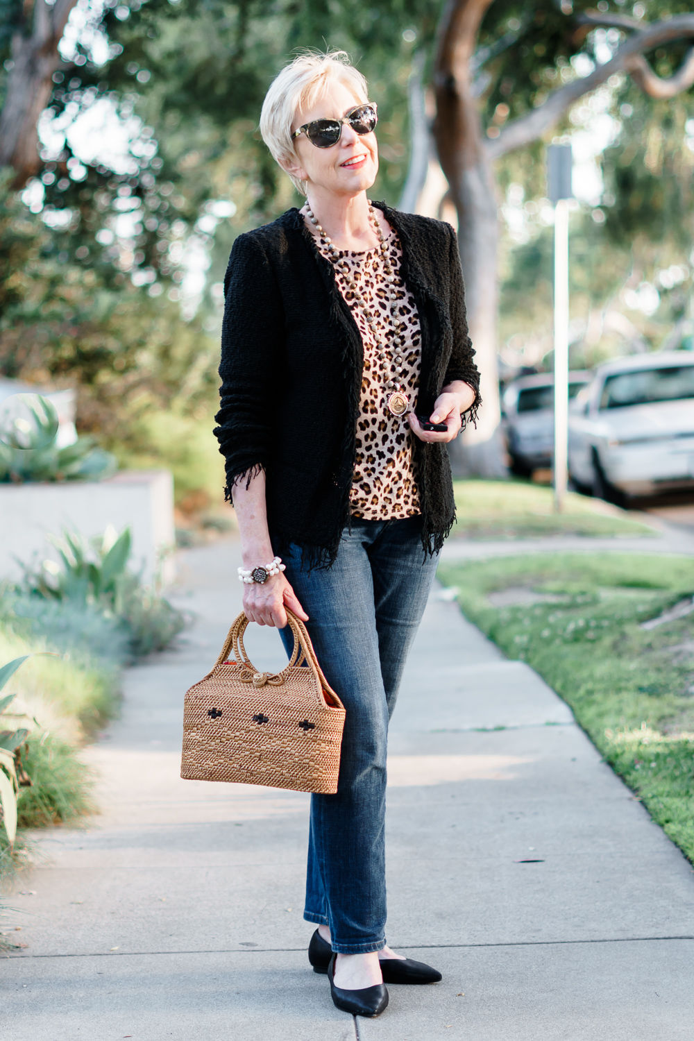 Susan B. of une femme d'un certain age wears an IRO fringe jacket, leopard print tee and jeans.