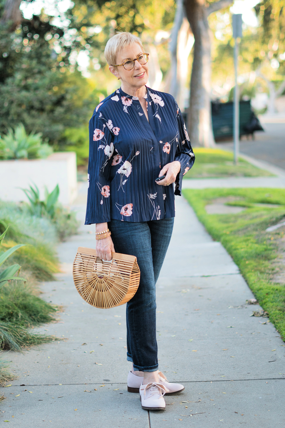 Susan B of une femme d'un certain age wears a Vince pleated floral top in navy, bamboo bag, jeans, and Vionic Evelyn Darby oxfords in shell pink.