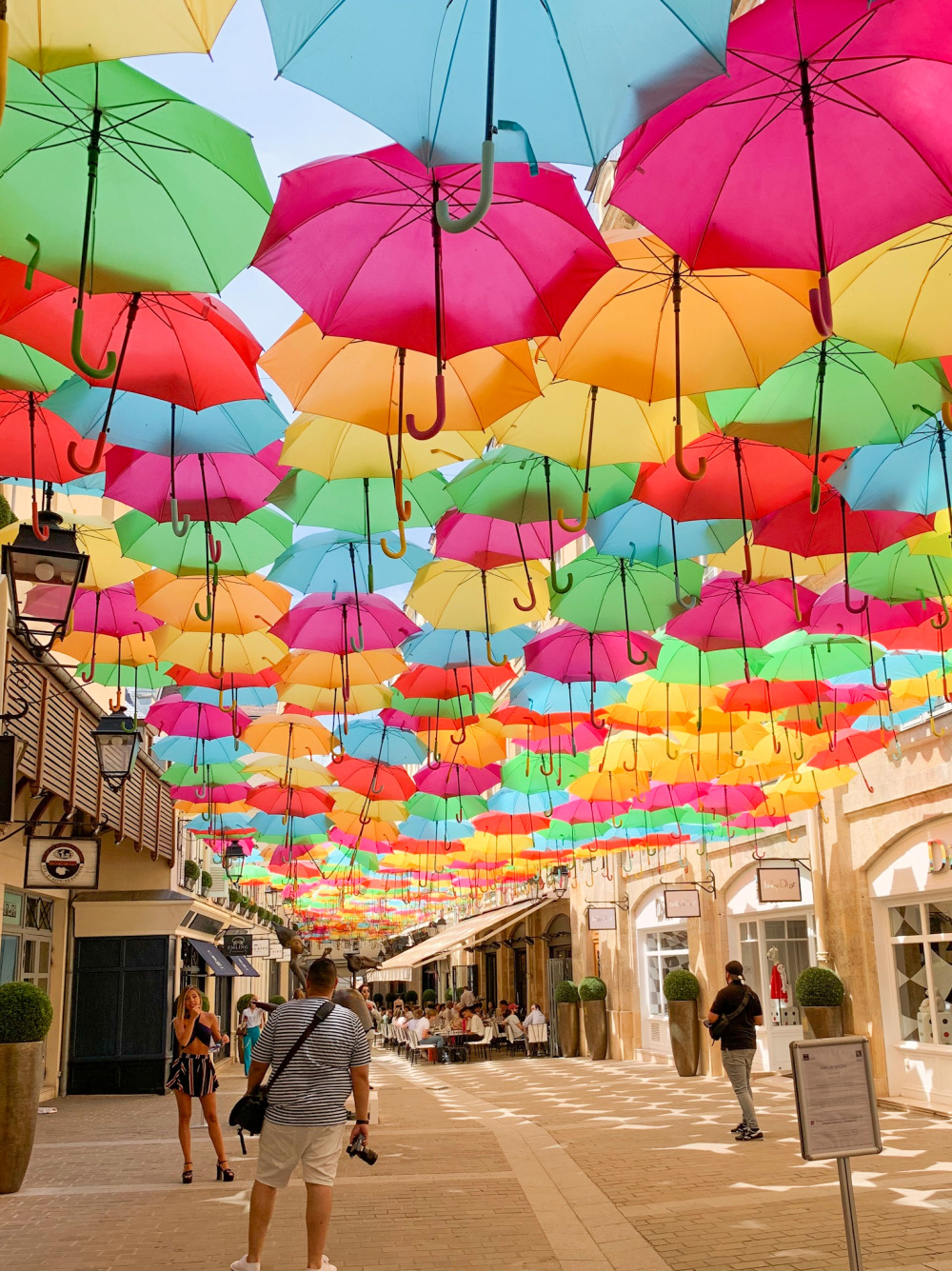 Colorful umbrella installation over Le Village Royal passage in Paris. Details at une femme d'un certain age.