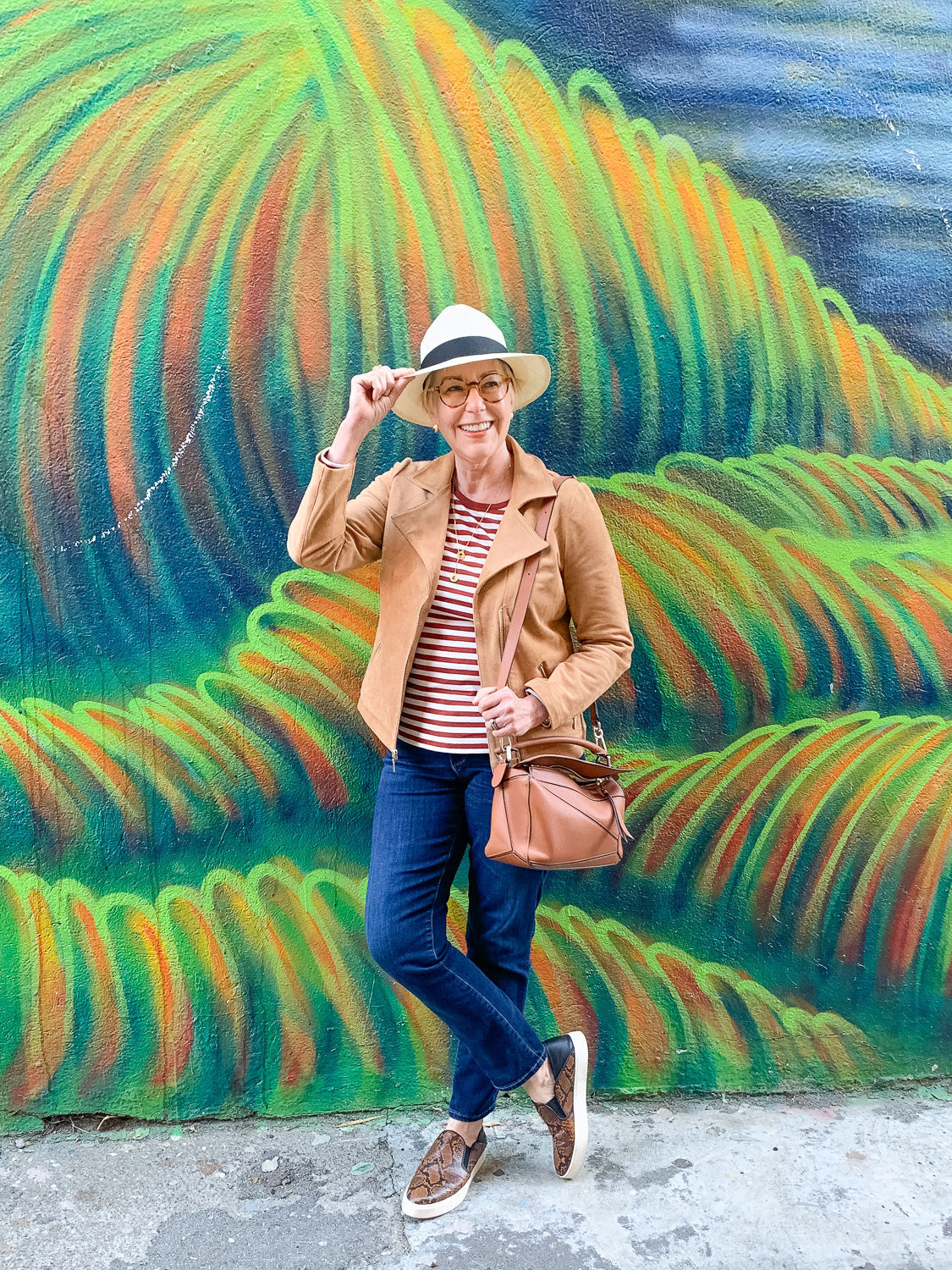 Susan B. wears a travel outfit with jeans, a striped tee, faux suede jacket and fedora hat. Details at une femme d'un certain age.