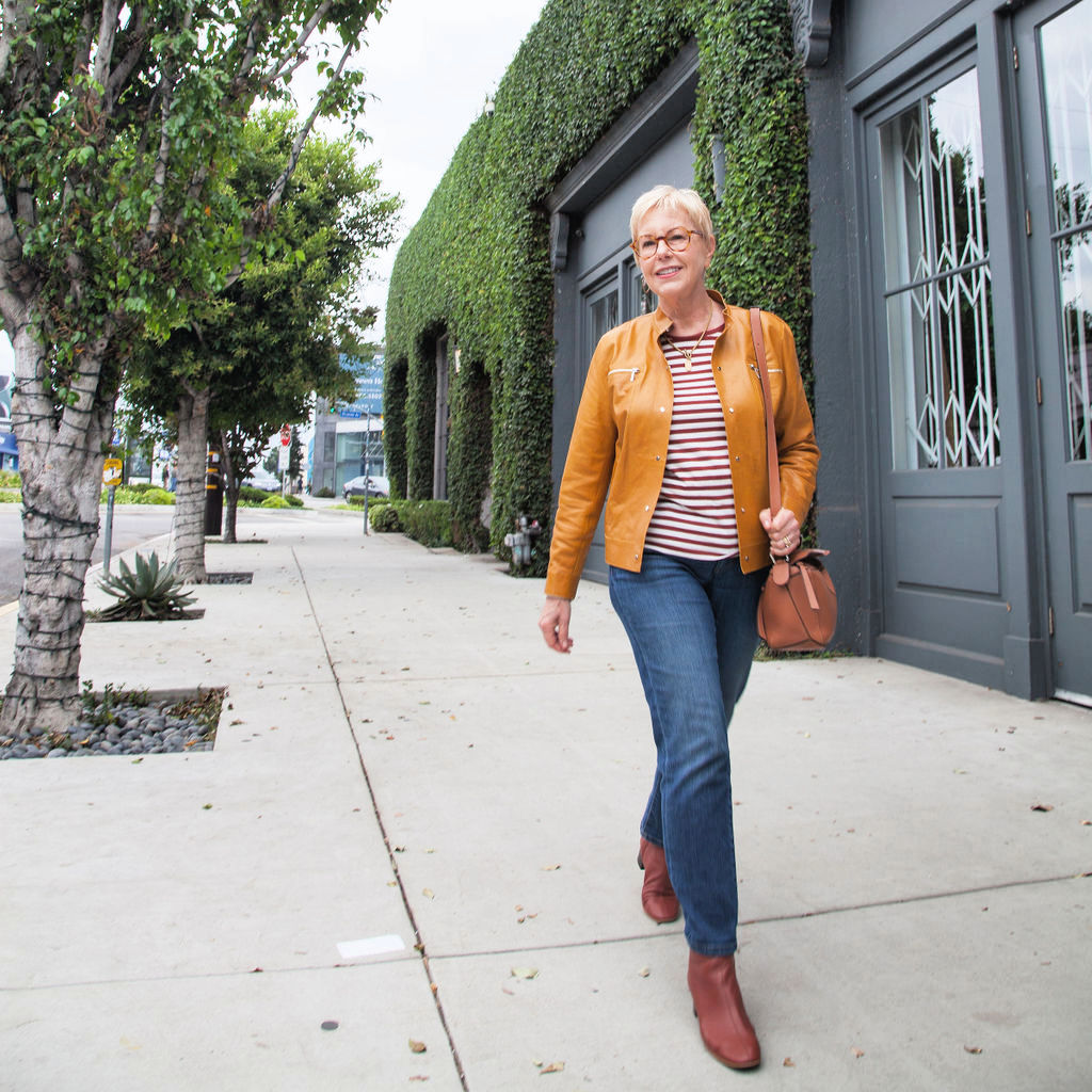 Susan B of une femme d'un certain age in a casual leather jacket outfit with striped tee and jeans.