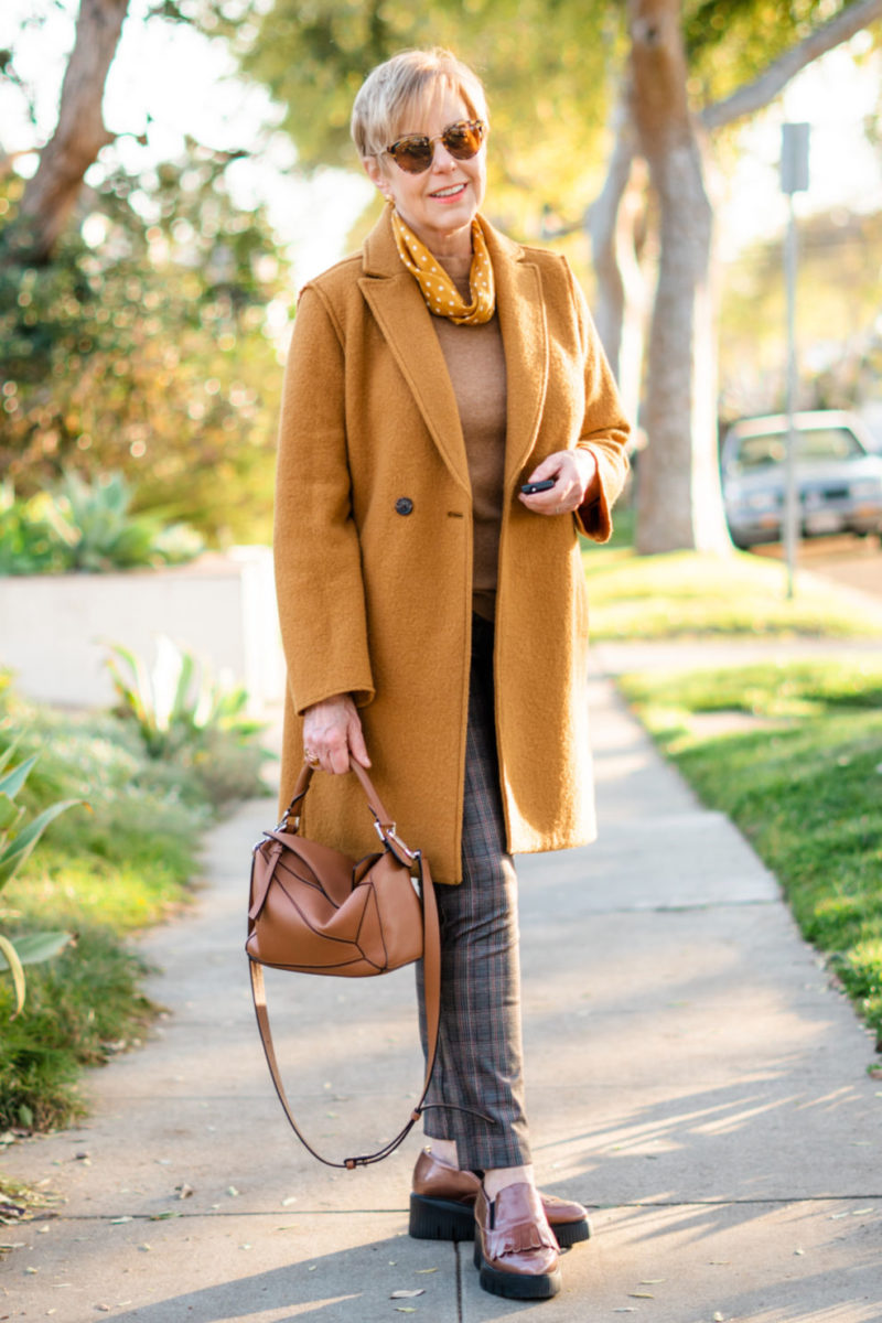 Susan Blakey of une femme d'un certain age wears a polished casual outfit with camel and plaid separates, mustard accents.