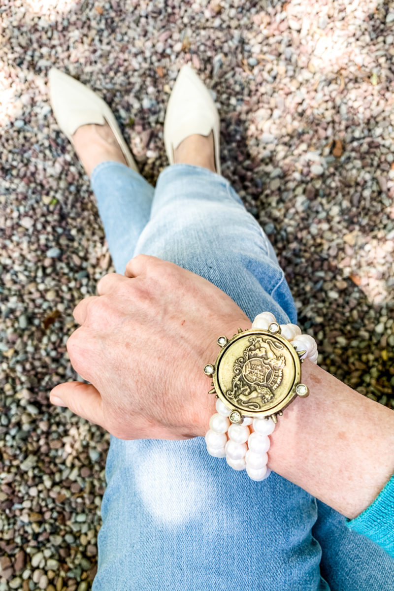 Susan B. wears a French Kande pearl bracelet with vintage medalion, light wash jeans and bone loafers. Details and more casual pearl jewelry at une femme d'un certain age.