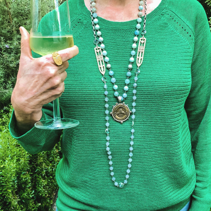 Detail: Susan B. wears a green linen sweater, French Kande necklaces and gold ring. Info at une femme d'un certain age.