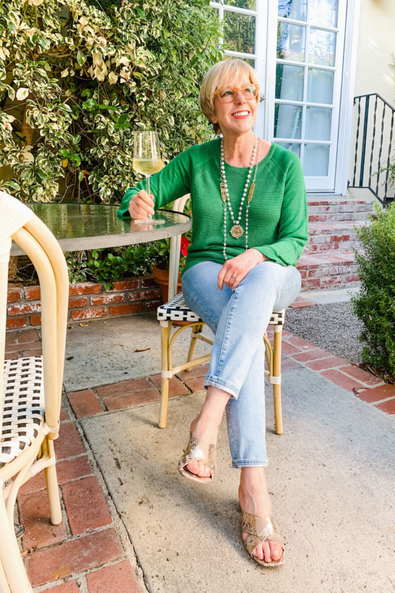 Susan B of une femme d'un certain age wears a green linen sweater, French Kande necklaces and Paul Green slide sandals.