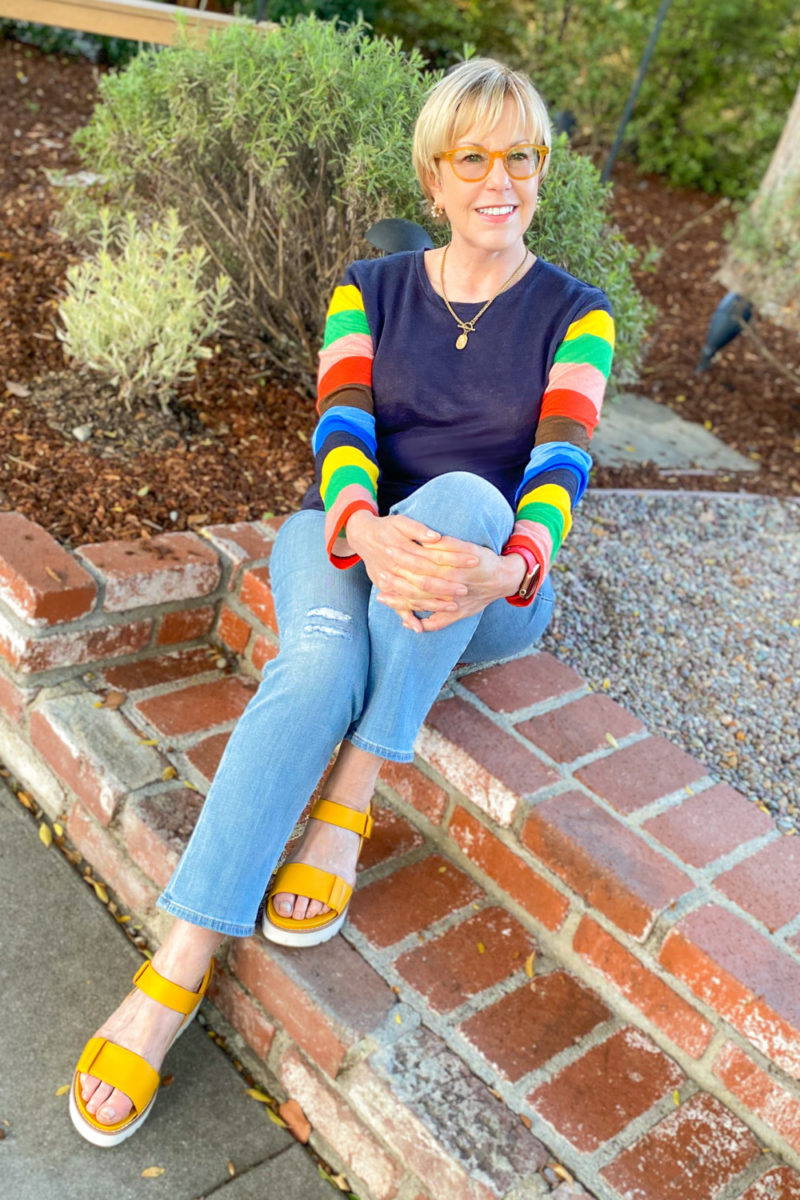 Susan B. wears a linen tee with striped sleeves, light wash jeans and yellow sandals. More outfit ideas for light wash jeans at une femme d'un certain age.