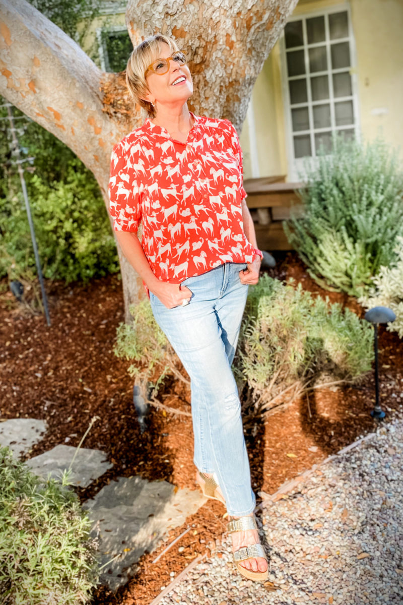 Susan B. wears a poodle print shirt with light wash jeans and gold wedge sandals. Details at une femme d'un certain age.