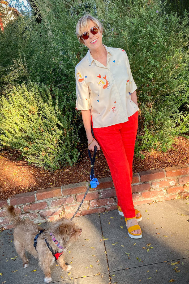 Susan B. wears a bright summer outfit with red linen pants, a printed top, and yellow platform sandals. Details at une femme d'un certain age.