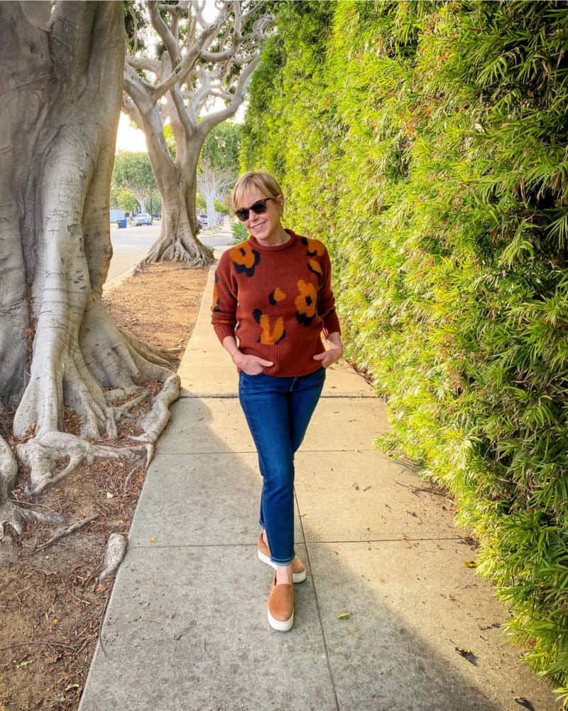 Susan B. wears an abstract leopard print sweater, dark wash jeans and slip-on sneakers. Details at une femme d'un certain age.