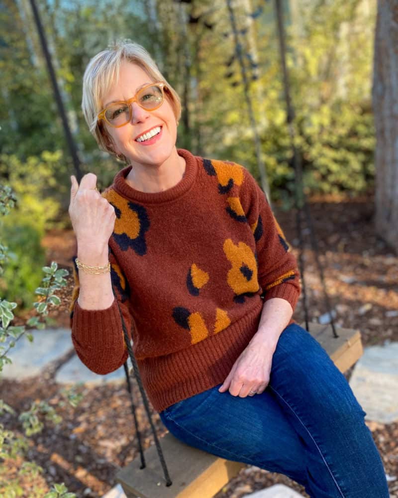 Susan B sits on a swing wearing a leopard printed sweater and jeans. Details at une femme d'un certain age.