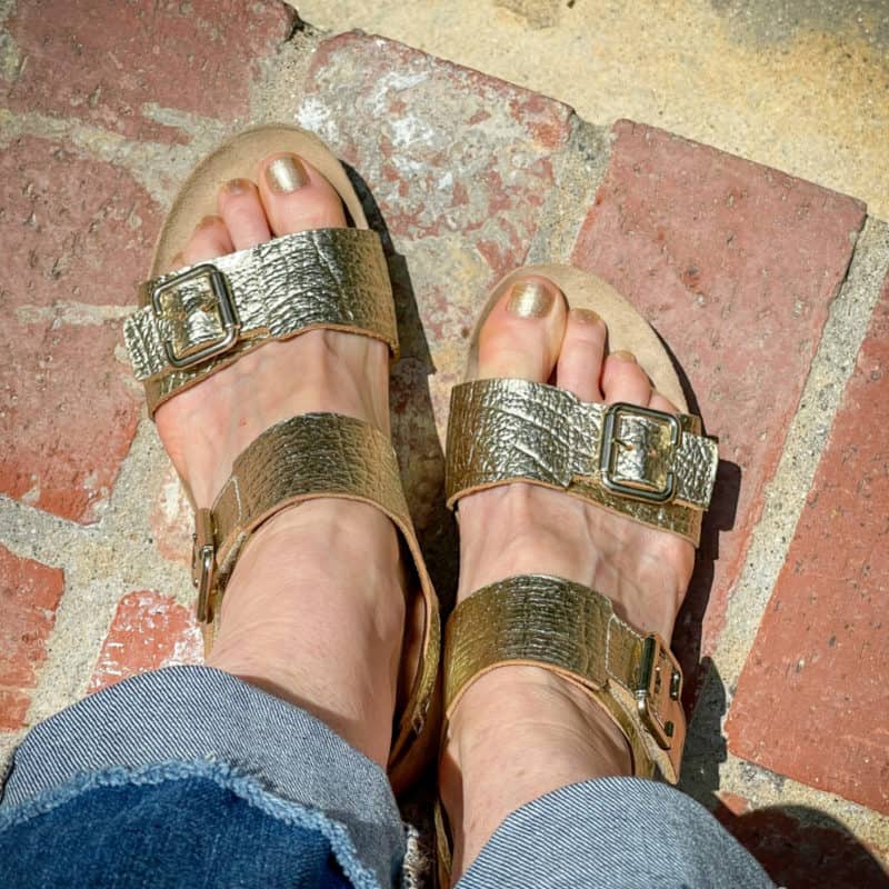 Susan wears gold sandals and gold nail polish on toes.