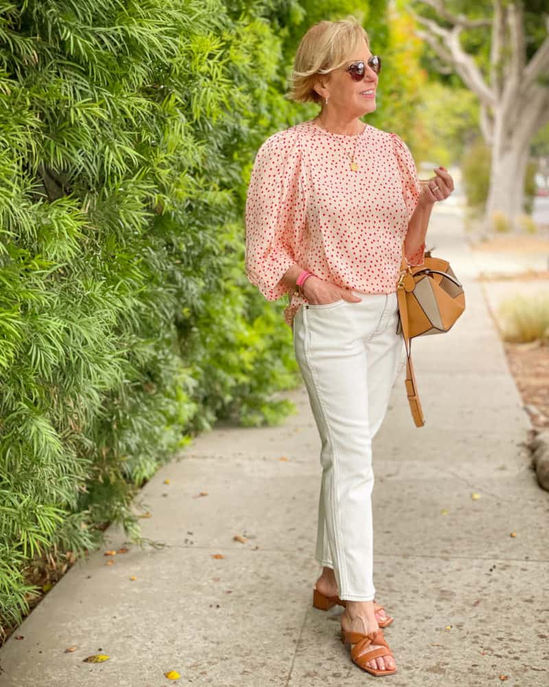 Susan B. wears a Samsoe Samsoe polka dot top, J.Crew white jeans, Vince sandals, and Loewe small puzzle bag.