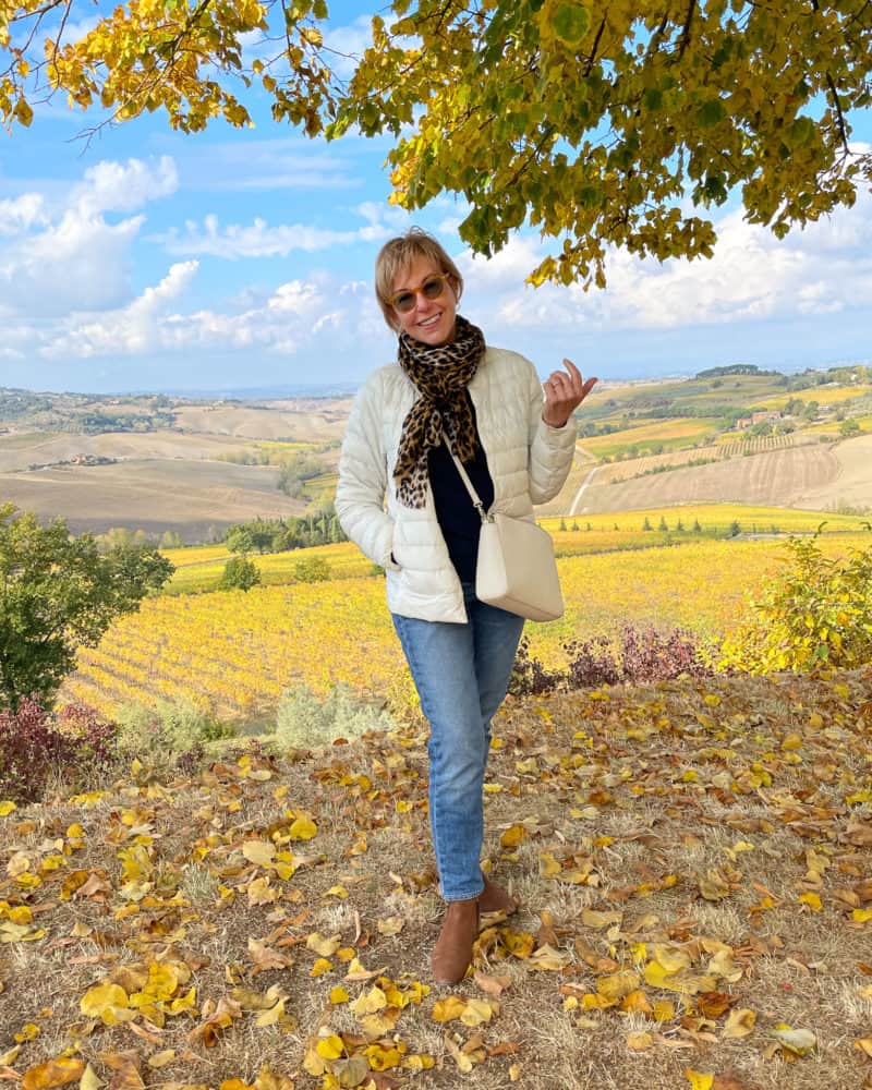 Susan B in Tuscany with gold vineyards in background. Travel outfit for a day of wine tasting.