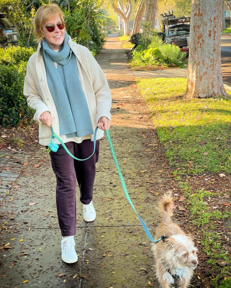 Susan B. wears an EILEEN FISHER scarf, jacket, top, and pants to take Gigi for a walk.