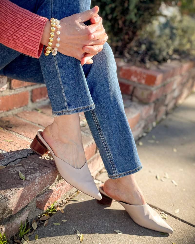 Detail: Susan B. wears Franco Sarto beige mules, medium wash jeans, a gold bead and pearl bracelet.