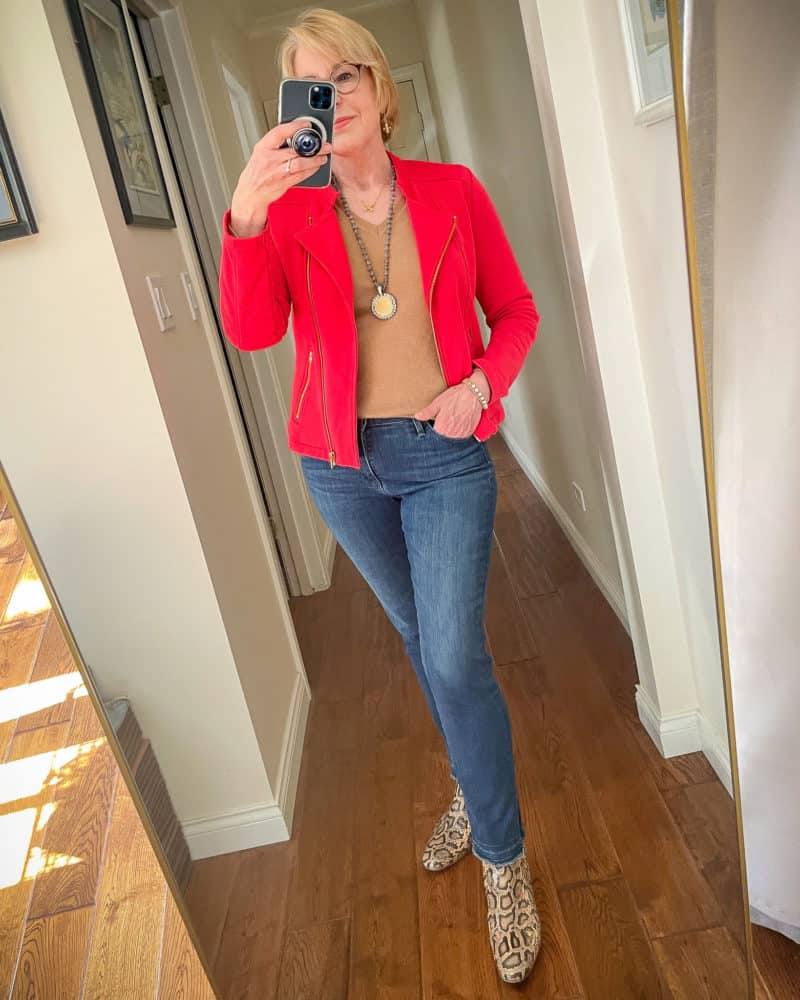 Susan B. wears a red moto jacket, camel v-neck cashmere sweater, French Kande necklaces, blue jeans and snake print booties.