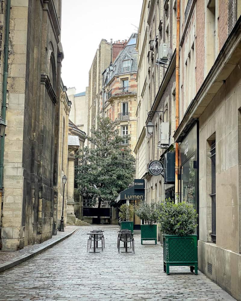 Side street with green planters and signs in Paris.