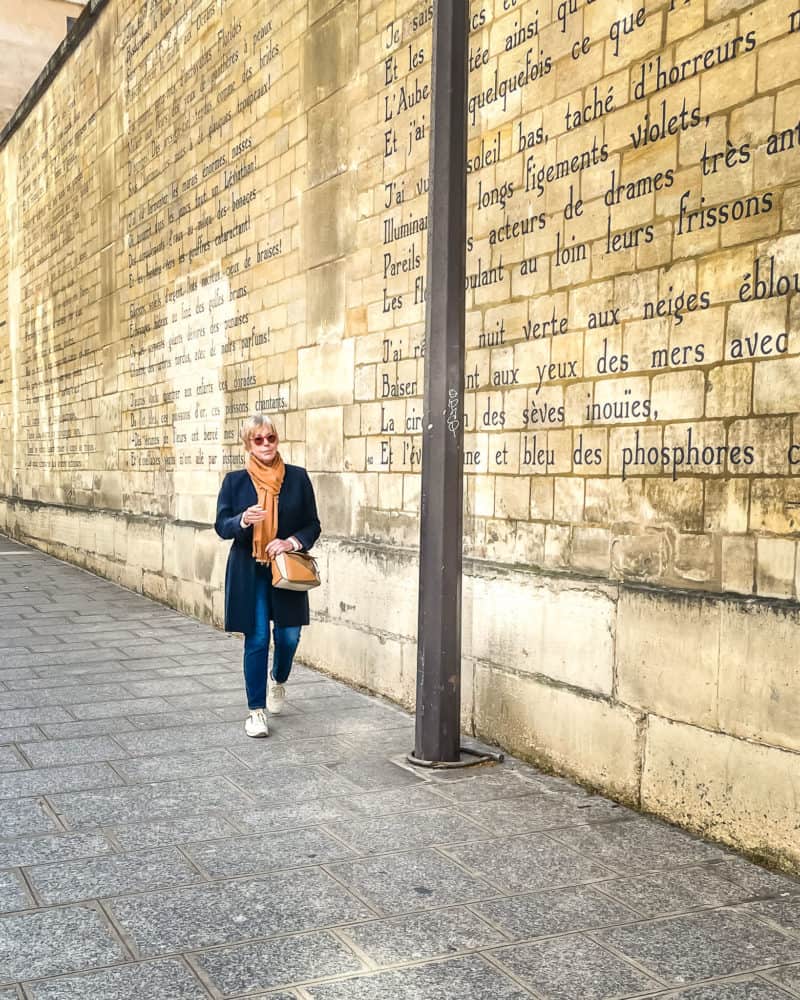 Susan B. walking along wall with Bateau Ivre poem by Rimbaud.