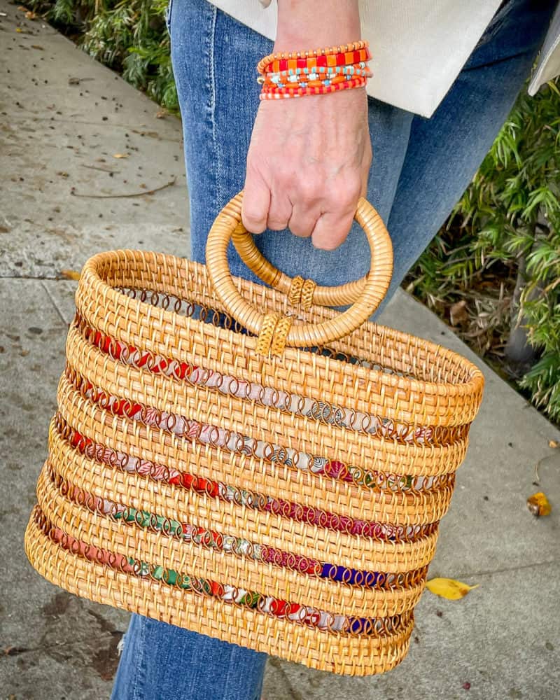 Detail: Susan B. wears Roxanne Assoulin orange and red bracelets, carries a Cult Gaia rattan bag with round handles.