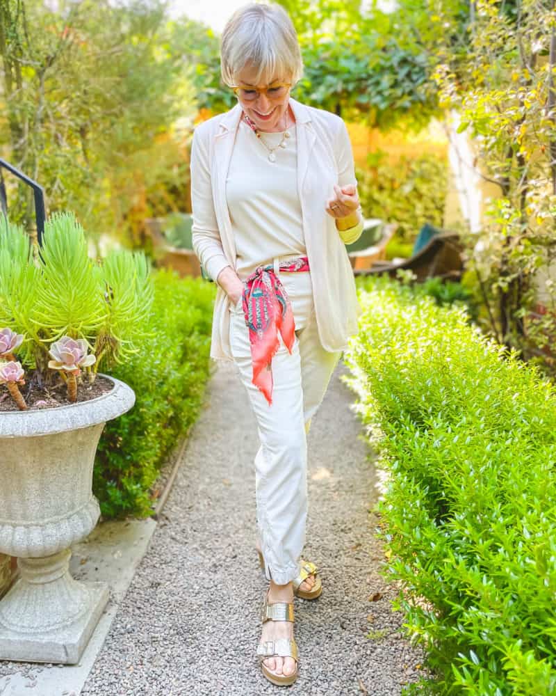 Susan B. wears an ivory outfit with an Emma J Shipley Odyssey pink silk scarf as belt.