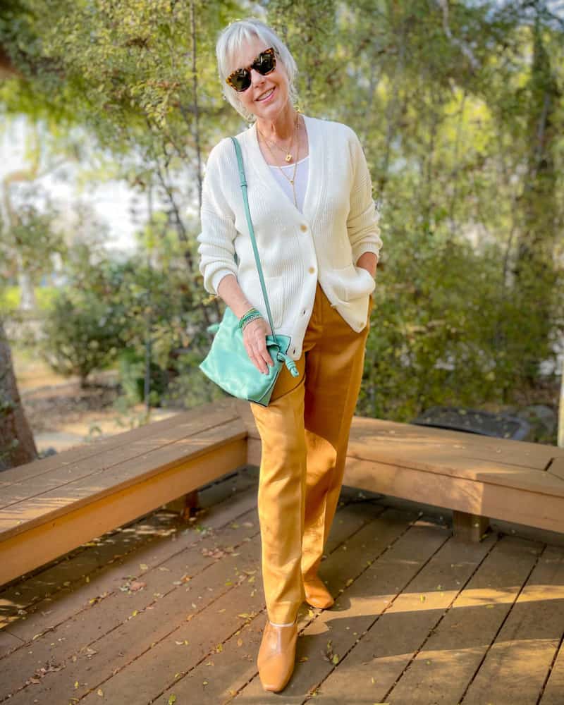 Susan B. wears a relaxed v-neck cardigan and camel trousers, Loewe small Flamenco bag.