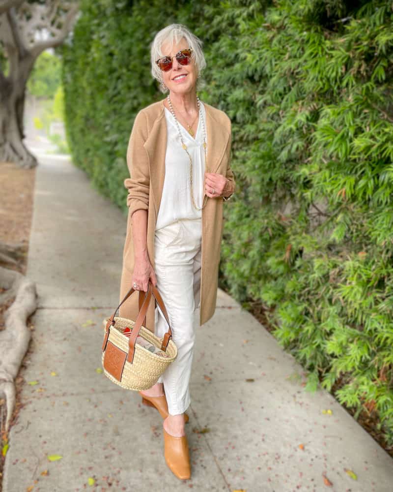 Susan B. wears a tonal fall outfit in ivory & camel, carries a Loewe straw bag.