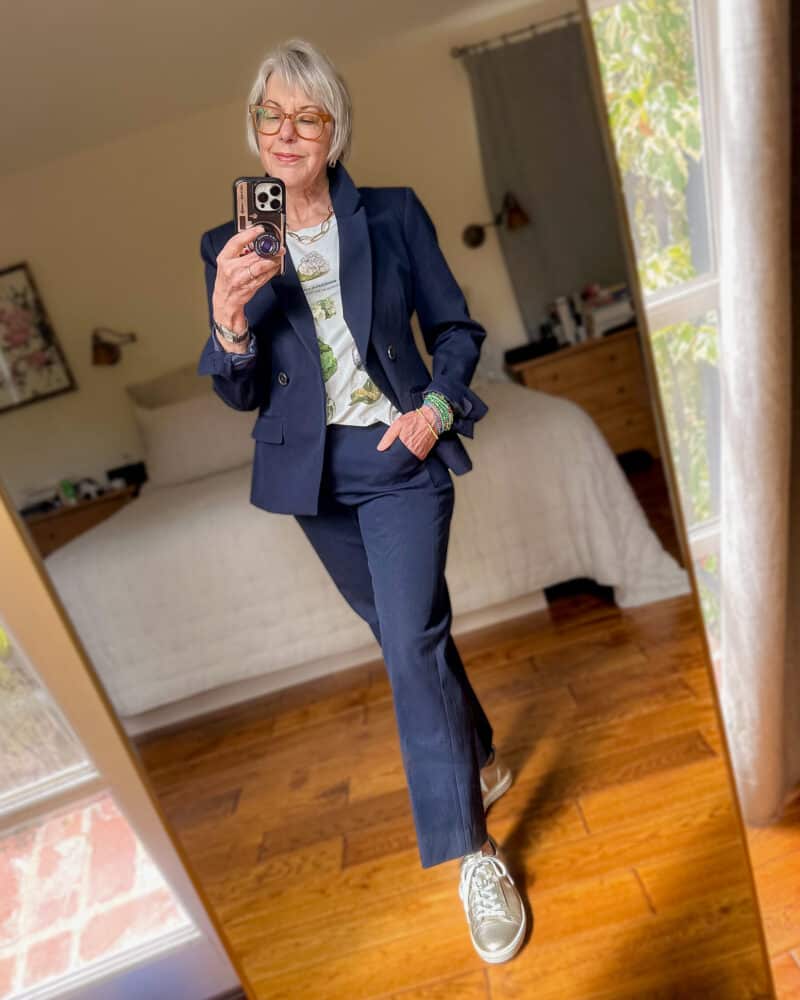 Susan B. styles a navy suit casually with a graphic tee, colorful bead bracelets, and gold metallic sneakers.