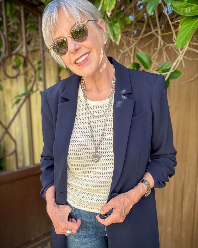 Susan B wears a navy Cinq a Sept Khloe blazer, crochet vest, sunglasses and silver tone necklaces.