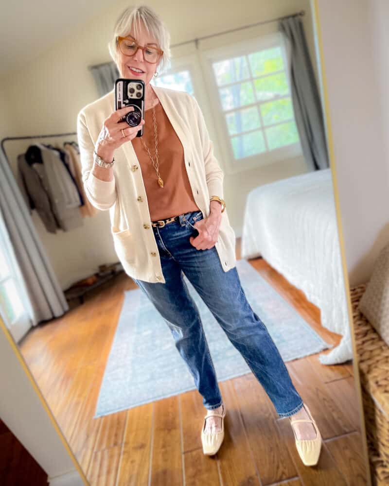 Susan B. wears a relaxed elegant outfit with a cashmere cardigan, silk tee, leopard belt, slim straight leg jeans, and slingback flats.