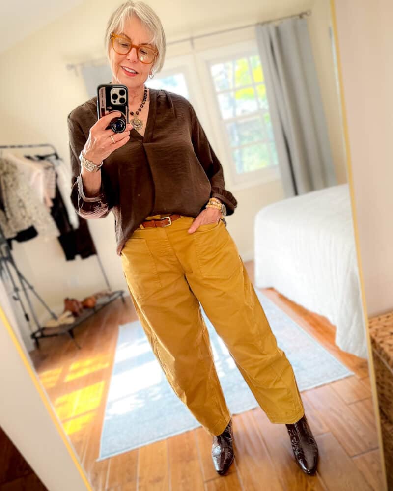 Susan B wears going-out look with slouchy trousers, medallion necklace, dark brown top, brown croc-print boots.