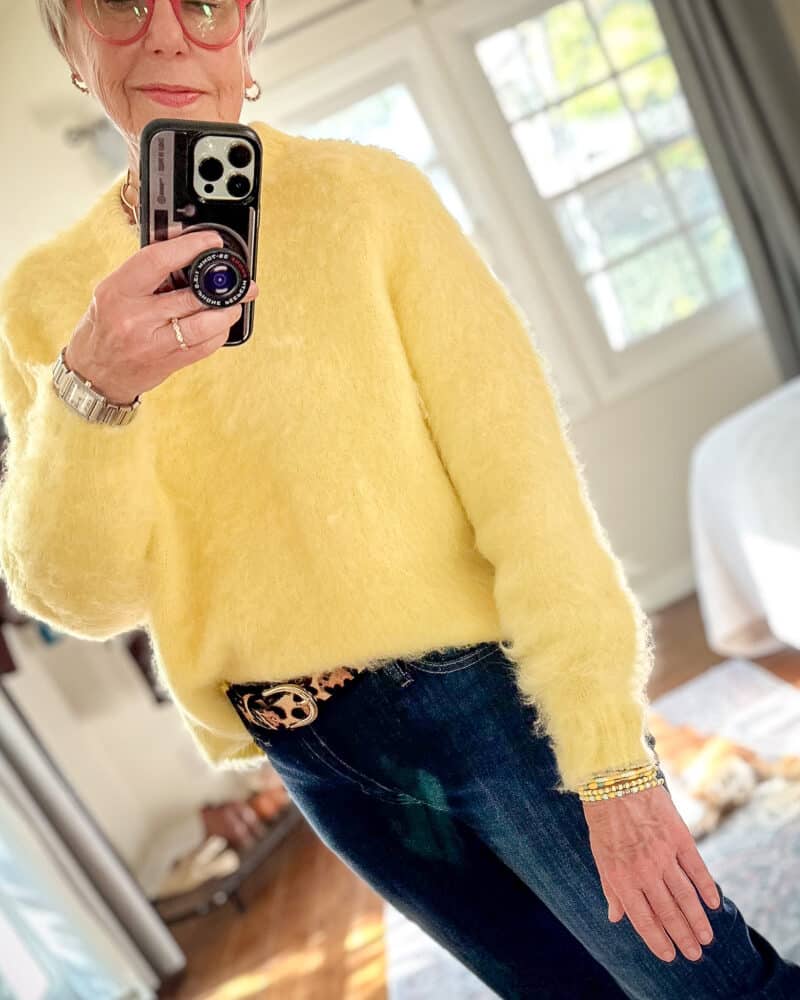 Susan B. wears a yellow brushed v-neck sweater, leopard belt, and jeans.