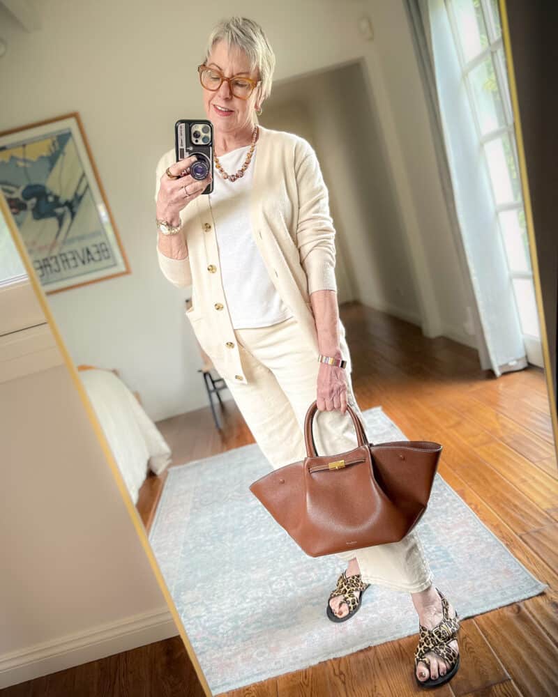 Susan B. wears a monochromatic look in ecru/ivory with a brown necklace, bag, and leopard print sandals.