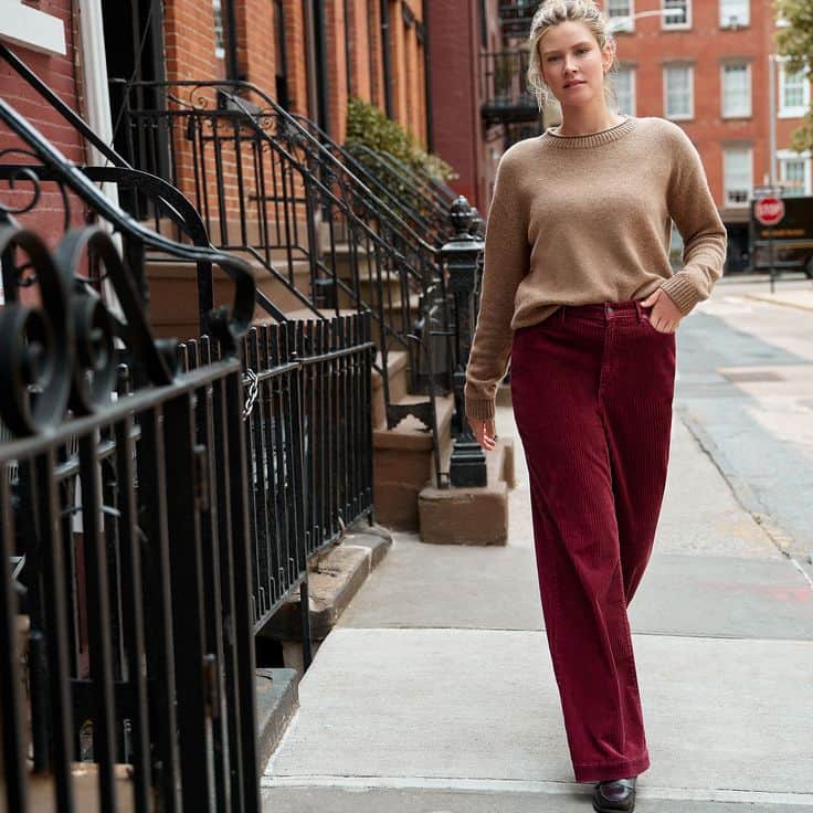Women walking on sidewalk wears Lands' End camel sweater and burgundy corduroy pants.