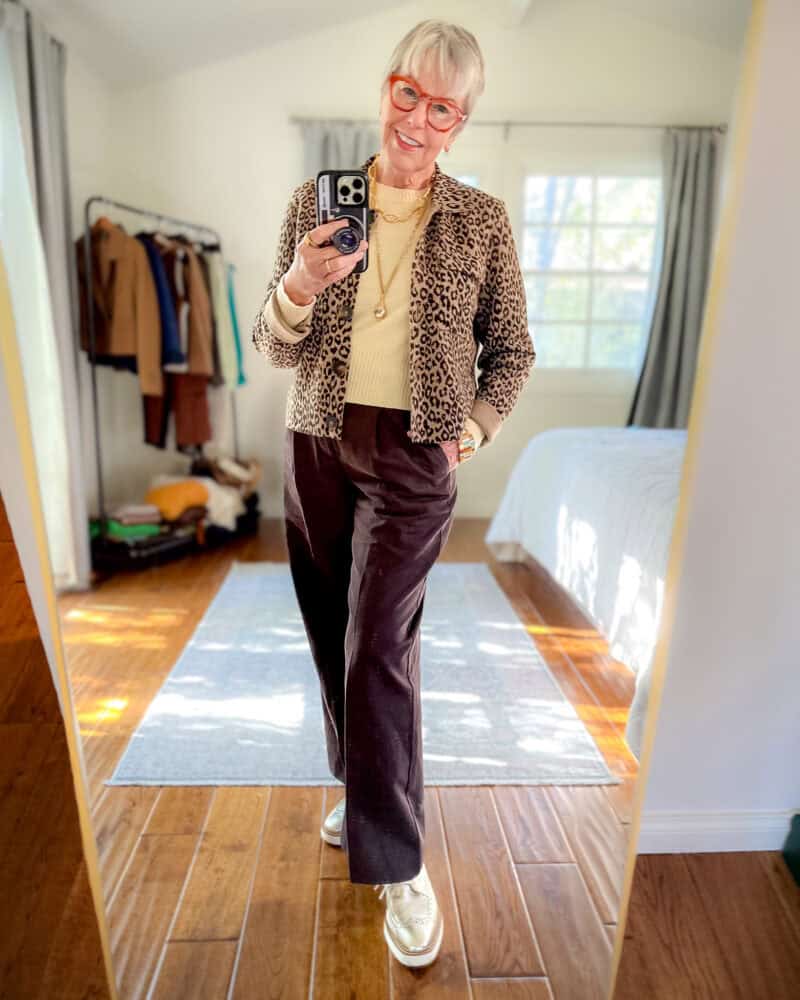 Winter capsule wardrobe exercise: Susan B. takes a mirror selfie wearing a Sezane leopard print collared cardigan, butter yellow sweater, brown pleated trousers, gold platform oxfords.