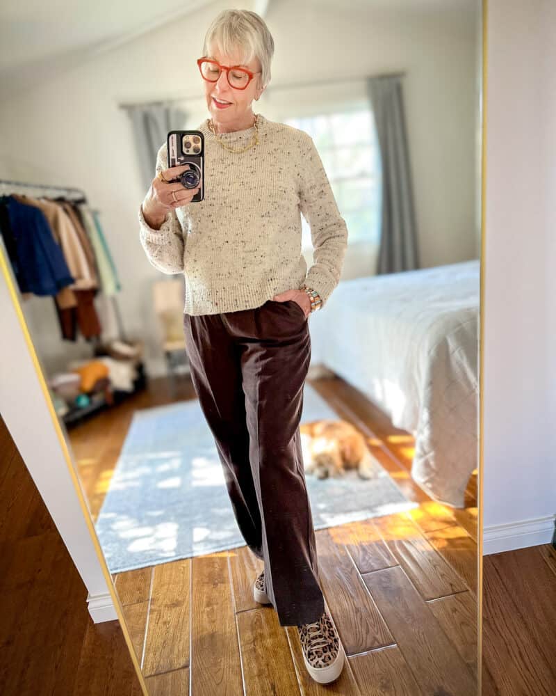 Susan B. takes a mirror selfie wearing Tibi confetti sweater, Madewell slouchy straight pants, leopard print sneakers.