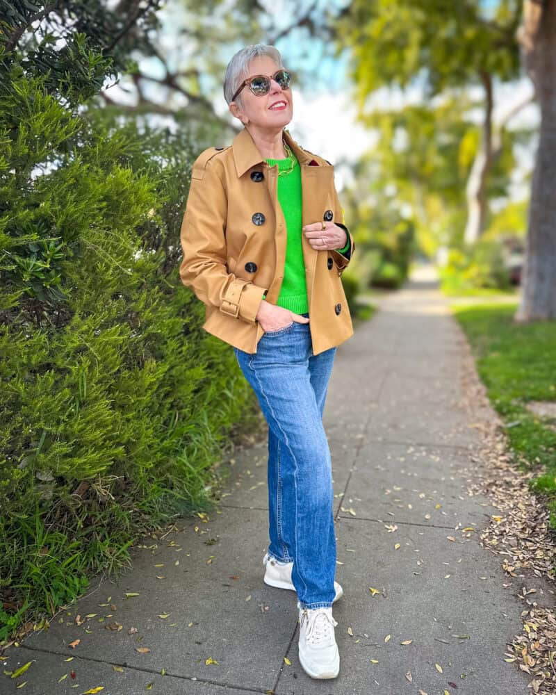 Susan B. wears a Boden cropped trench jacket, green Banana Republic sweater, straight leg jeans, sneakers.