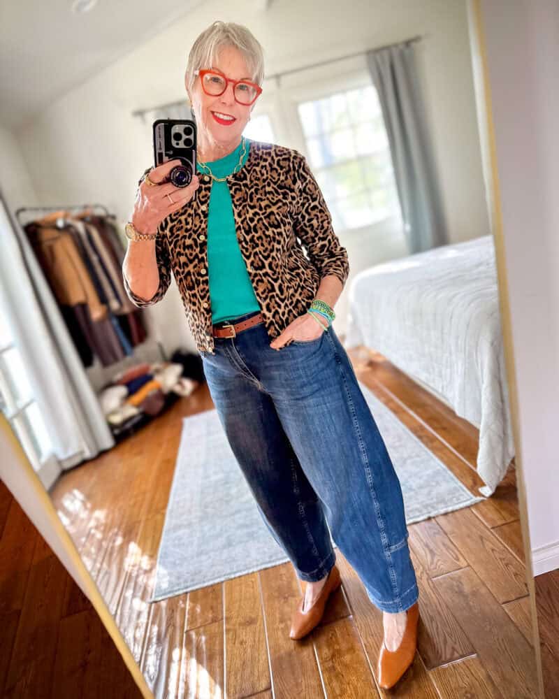 Susan B. wears a leopard print cashmere cardigan, bright aquamarine tee, green bracelets, brown belt and shoes, barrel leg jeans.