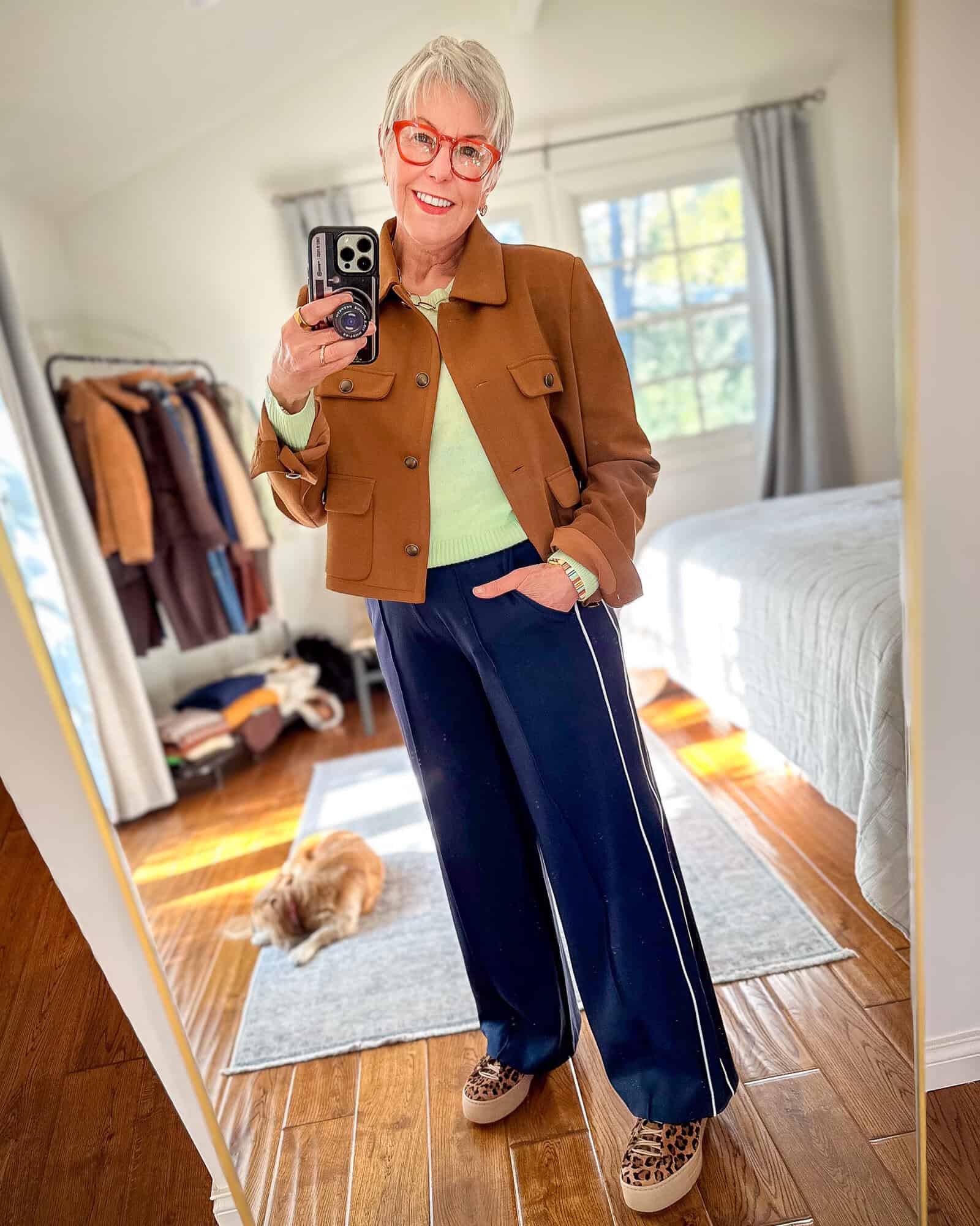 Susan B. wears a brown cropped utility jacket, mint green sweater, navy track pants with a side stripe, leopard sneakers.