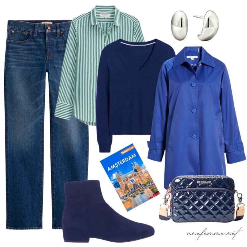 Travel outfit idea with jeans, striped shirt, navy v-neck sweater, blue raincoat, navy suede booties, crossbody camera bag.