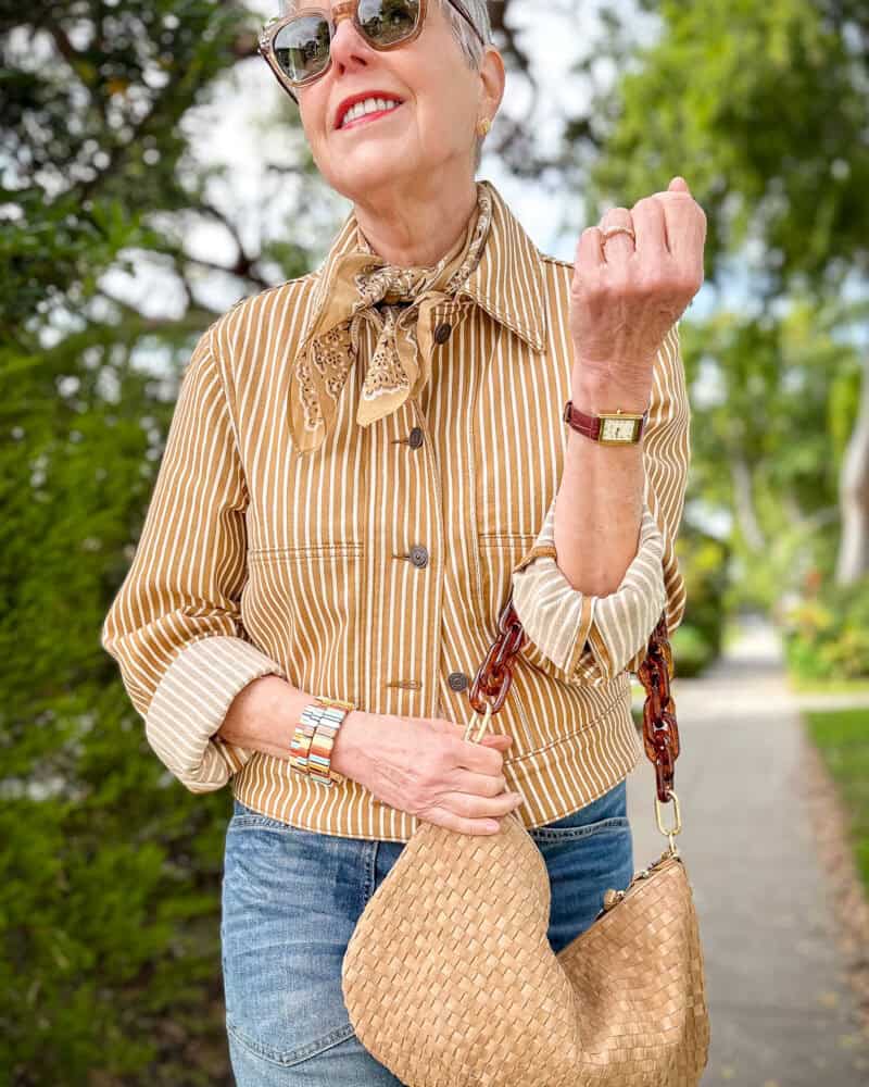 Details: Susan B. wears a striped Me+Em jacket, tan bandana, striped Roxanne Assoulin bracelets, Clare V woven Moyen bag with resin strap, Heaven Mayhem watch.
